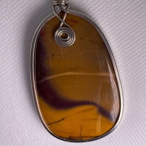 Amber color stone pendant with silver swirl.